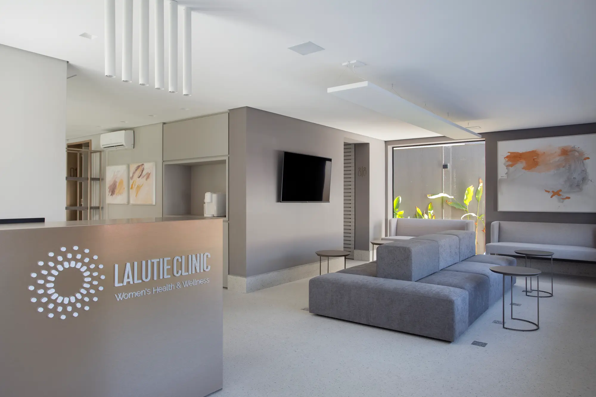 Sala de espera da Lalutie Clinic com sofás cinza e jardim interno
