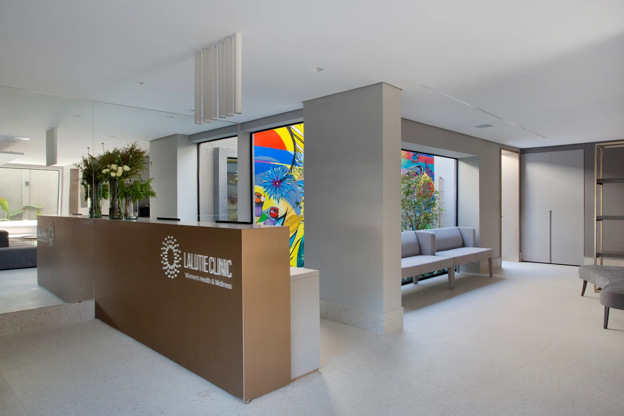 Recepção da Lalutie Clinic com balcão em bronze e mural colorido ao fundo