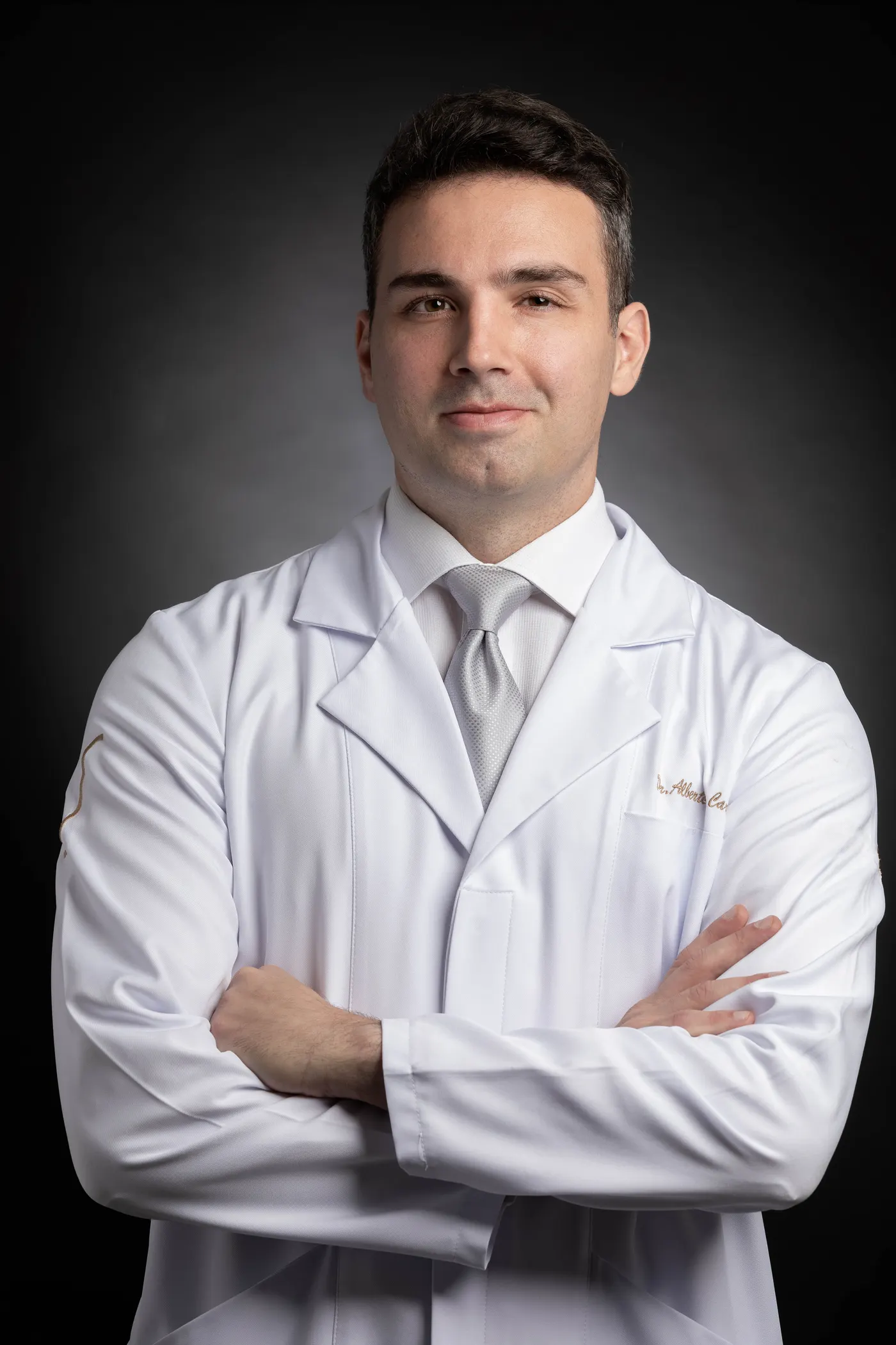 Dr. Alberto De Carli, médico do esporte, de jaleco e com os braços cruzados